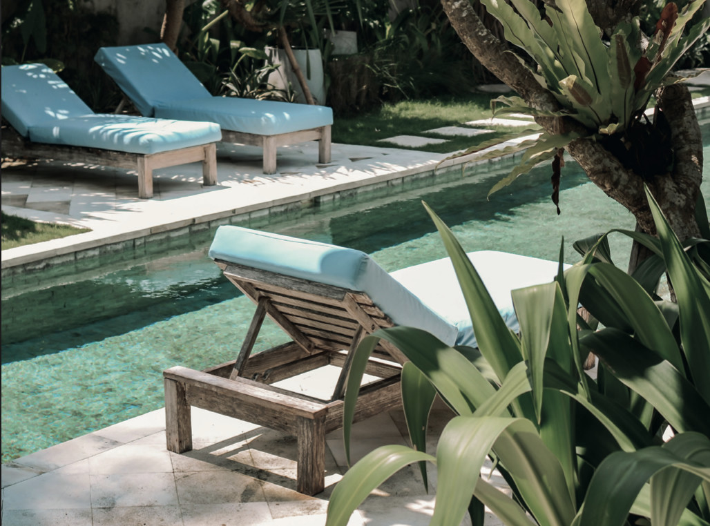 Transats au bord de la piscine d'une villa, dans un jardin verdoyant